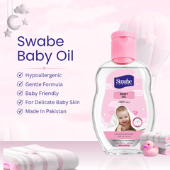 A bottle of Swabe Baby Oil with a pink cap and pink label, shown on a soft pink background with promotional text, folded towels, and small bath accessories. The Swabe brand name is visible on the bottle.